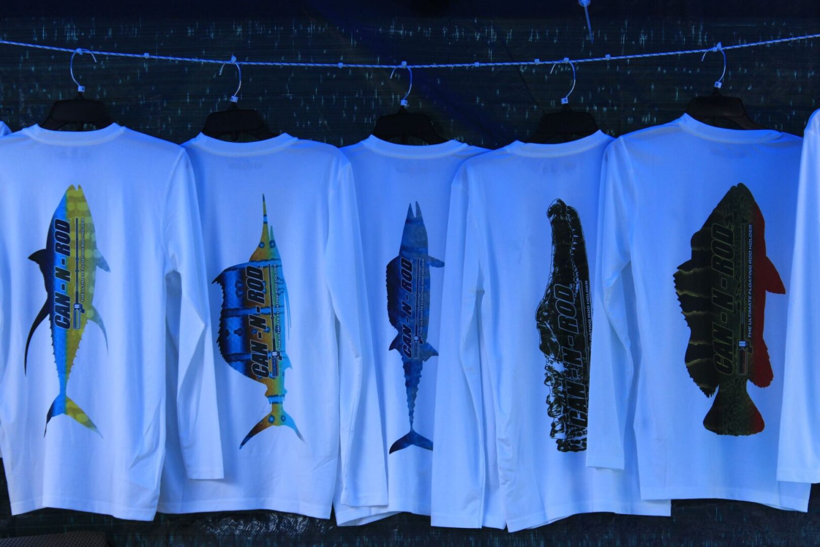 A group of fish on shirts hanging from clothes line.