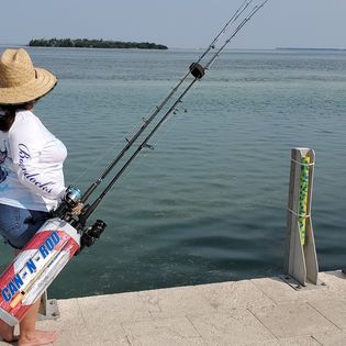 A person standing on the edge of a pier holding a fishing rod.