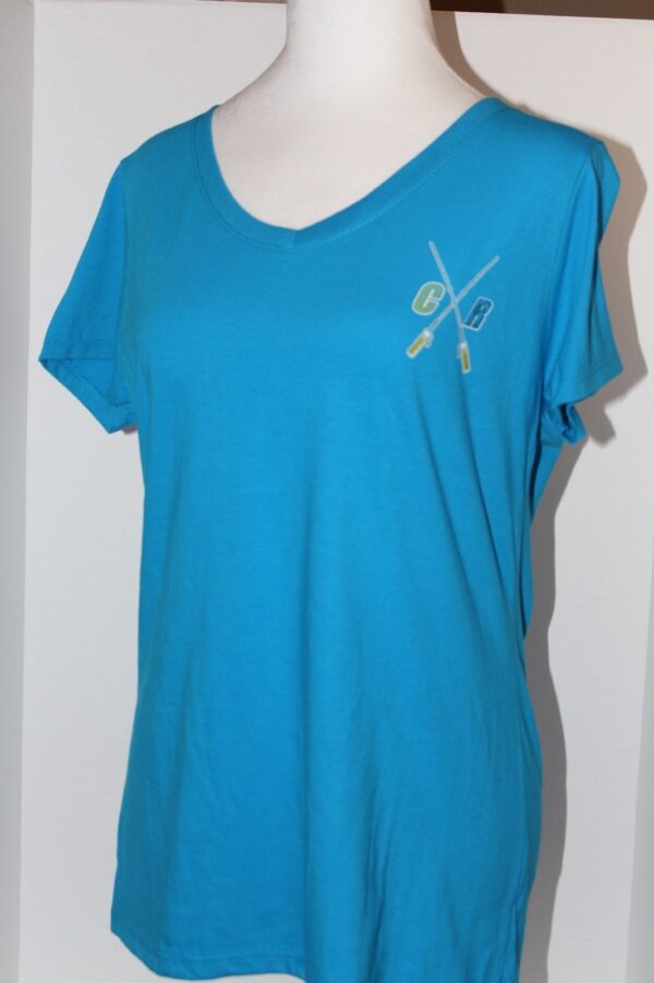 A blue v-neck t-shirt on a mannequin, featuring a small embroidered logo with scissors and a comb on the left chest area.